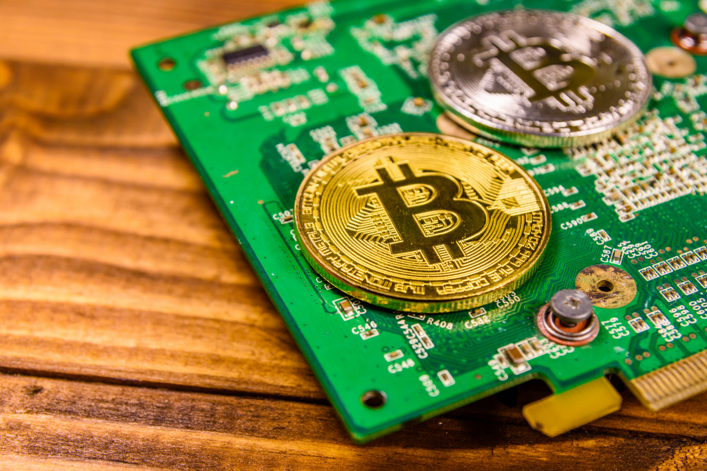 A close-up of a coin with the Bitcoin logo on a circuit board on a wooden table