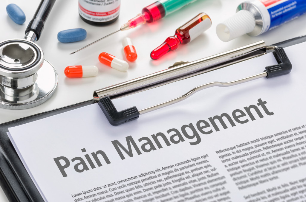 pain management title on a document in a clipboard with pills, injection, and a stethoscope at the top